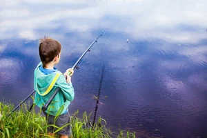 boy with a fishing rod standing by the water