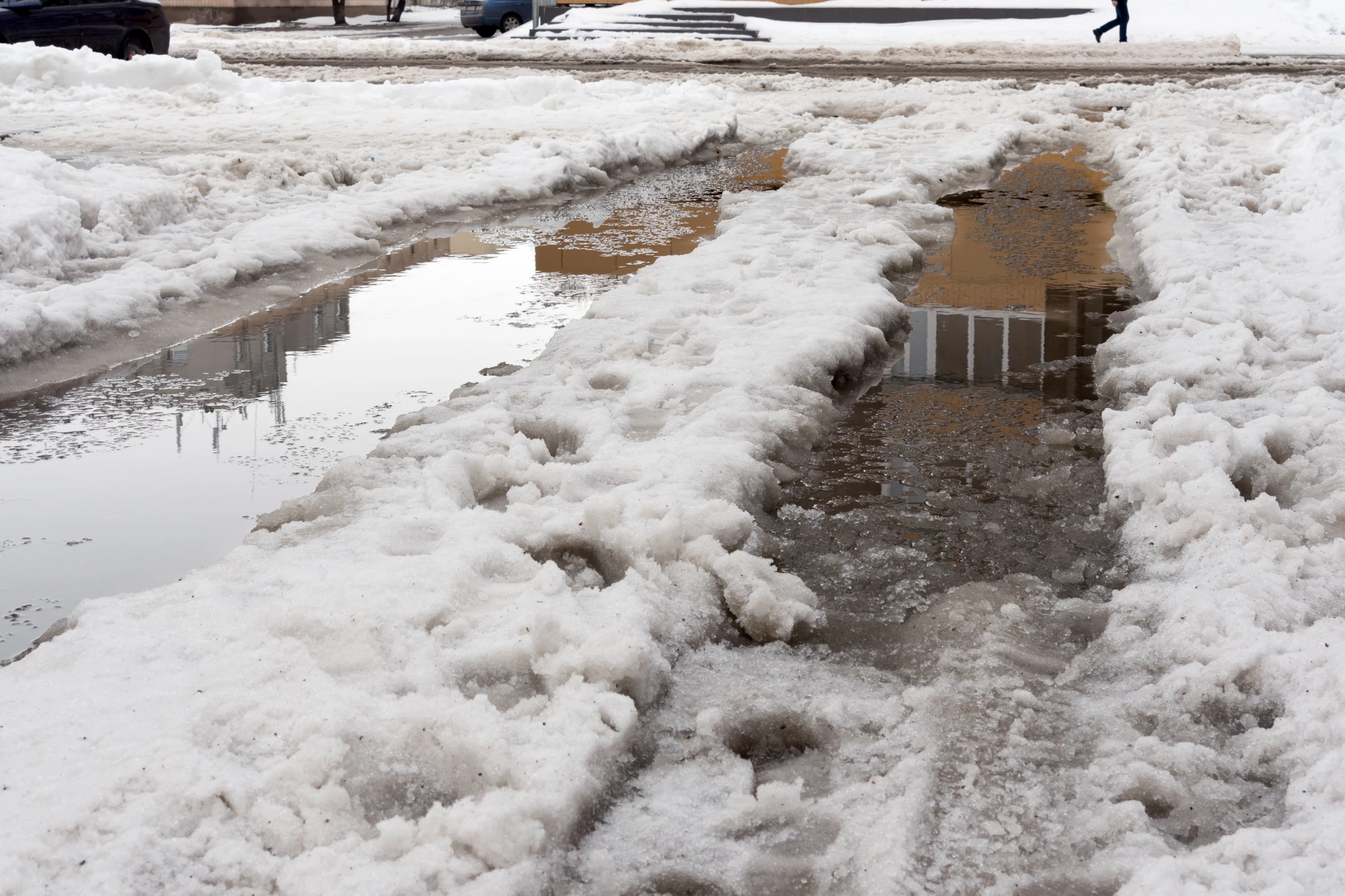 ice and snow in puddles spring. Thaw after winter in the city. Concept of bad water flow communication, deluge.
